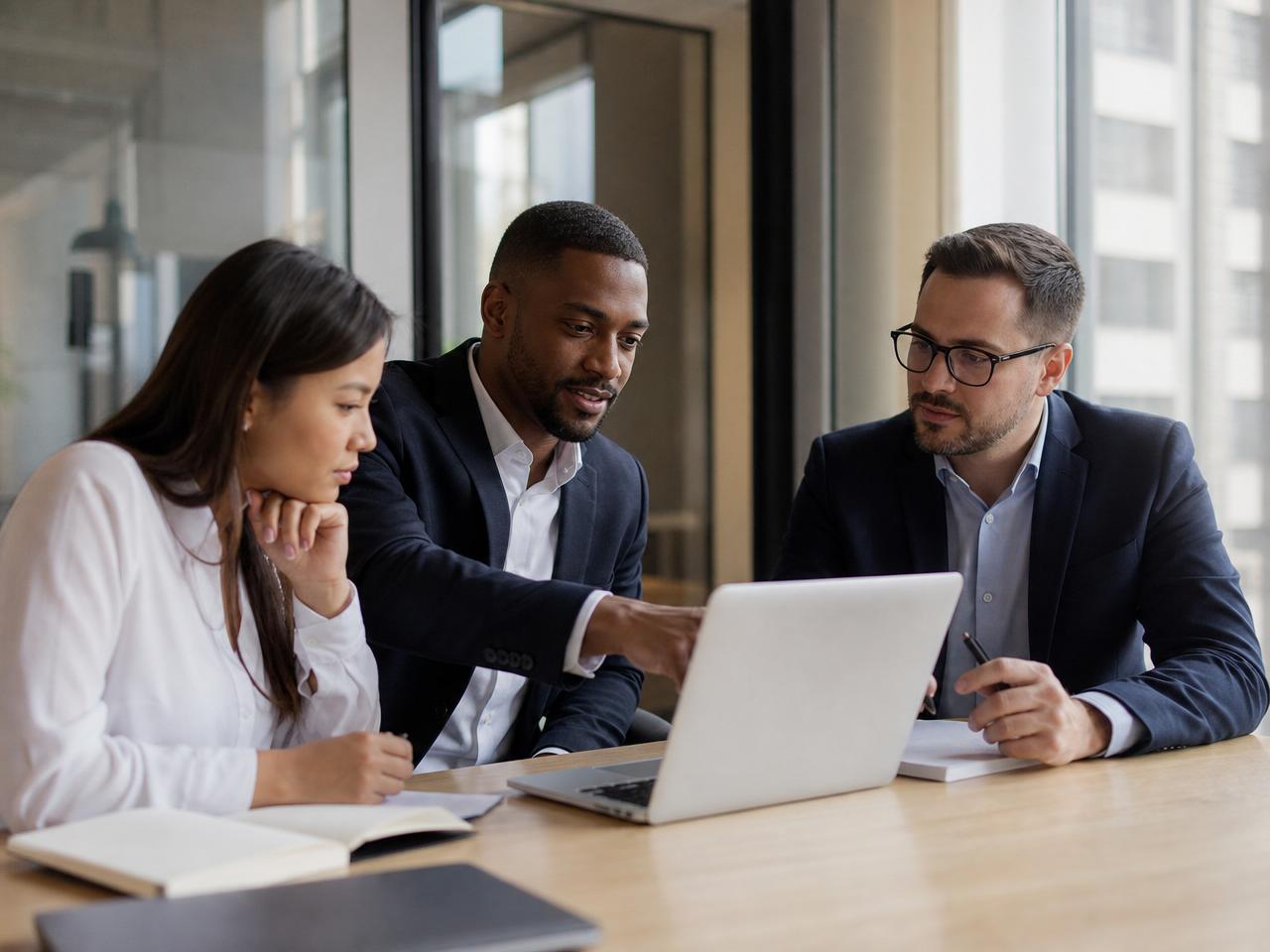 Three professionals collaborating around a laptop